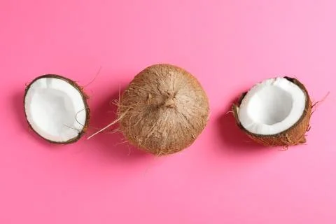 Two coconut one of which split on color background, space for text Stock Photos