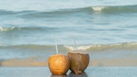 Two coconuts with straws for drinking on the background of the sea Stock Photos