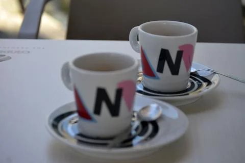 Two coffee cups with brewed coffee, white coffee cups and saucers with motifs Stock Photos