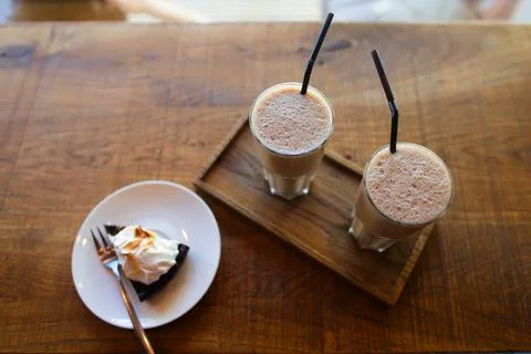 Two coffee drinks with drinking straw and slice of pie on saucer with fork stand Stock Photos