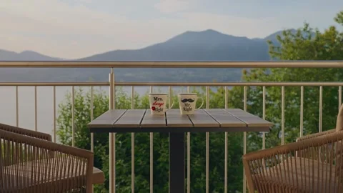 Two Coffee Mugs Centered on Balcony Table with Spectacular Lake and Mountain Stock Footage 340423041
