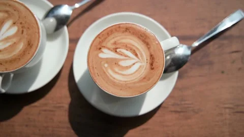 Two coffee mugs inside, standing on saucers and next to metal spoons. Video stock 234020134