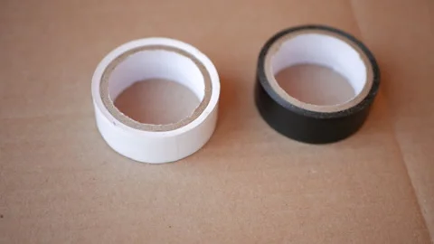 Two coils of electrical tape on a sheet of cardboard Video stock 153287015