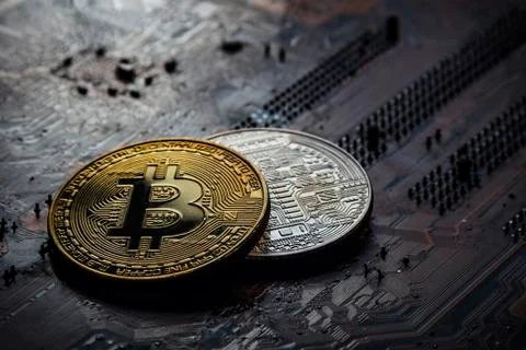 Two coins bitcoin on a dark background of an electronic computer board. Stock Photos