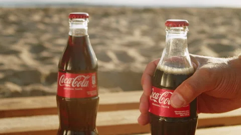 Two cold bottles of Coca Cola on wooden boards on a sunny day at the beach. Stock Footage 266355835