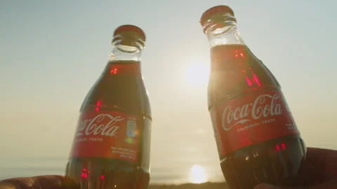 Two cold bottles of Coca-Cola are cracked on a hot summer day on the beach. Stock Footage 266356191
