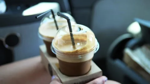 Two cold coffees in plastic cups with black straw inside, stand in cup holders Stock Footage 280305587