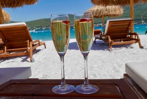 Two cold glasses of champagne with raspberry on white sand on the beach in an Stock-Fotos