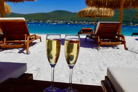 Two cold glasses of champagne with raspberry on white sand on the beach in an Fotos Stock