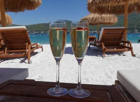 Two cold glasses of champagne with raspberry on white sand on the beach in an 库存照片