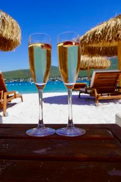 Two cold glasses of champagne with raspberry on white sand on the beach in an Stockfoto's