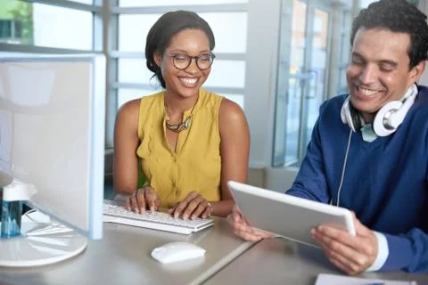 Two  colleages discussing ideas using a tablet and computer Stock Photos
