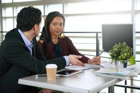 Two  colleages discussing ideas using a tablet and computer Stock Photos