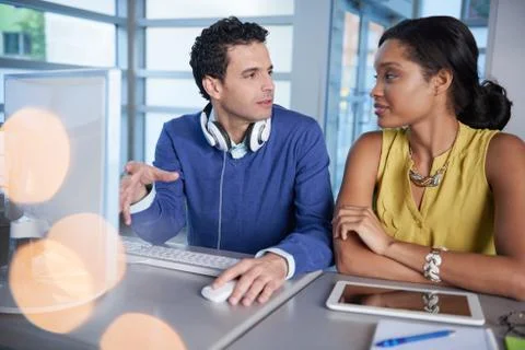 Two  colleages discussing ideas using a tablet and computer Stock Photos