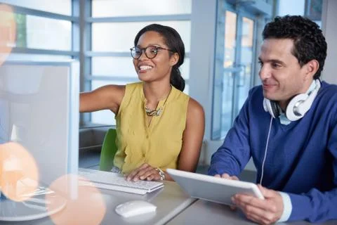 Two  colleages discussing ideas using a tablet and computer Stock Photos