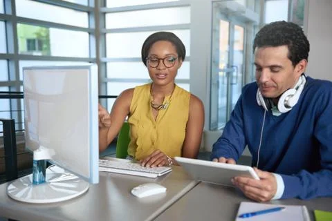 Two  colleages discussing ideas using a tablet and computer Stock Photos