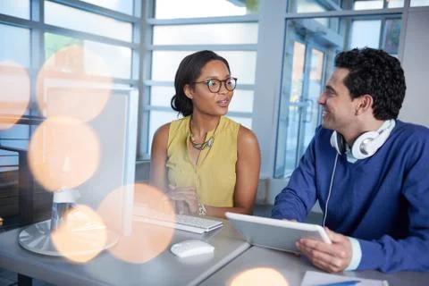 Two  colleages discussing ideas using a tablet and computer Stock Photos
