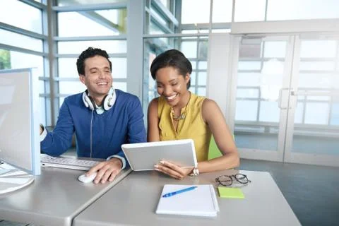 Two  colleages discussing ideas using a tablet and computer Stock Photos