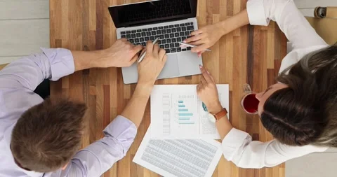 Two colleagues analyze financial data together on laptop, top view Stock Footage 276734516