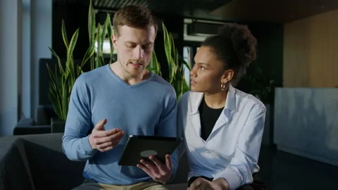 Two colleagues are being trained on a tablet while sitting in the office Stock Footage 195208162