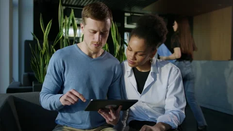 Two colleagues are trained on a tablet while sitting during working hours Stock Footage 195203508