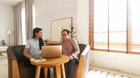 Two colleagues collaborate on a laptop in a bright, modern living room 動画素材 319010732