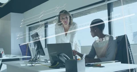 Two colleagues at desk operating laptop, pointing and analyzing biz timeline Stock Footage 332285268