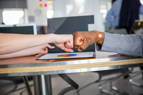 Two colleagues of different ethnicities join fists during a conference, agr.. Stock Photos