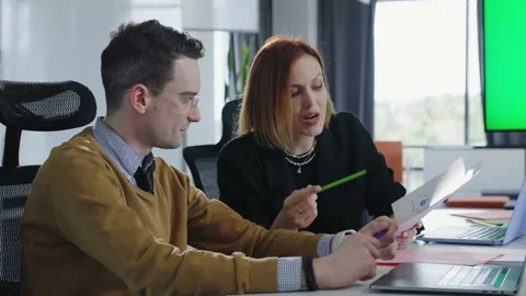 Two colleagues discuss the project sitting at a desk in the office Stock Footage 193586261