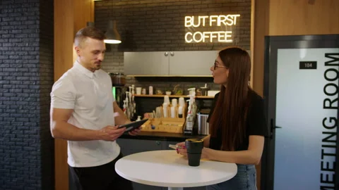 Two colleagues discuss a work project on a tablet in an office cafe Stock Footage 195204808