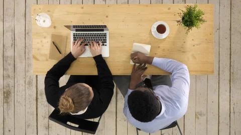 Two colleagues discussing data on laptop putting down notes Stock Photos