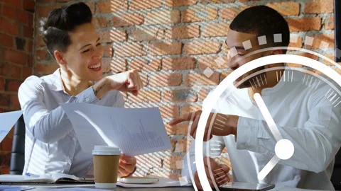 Two colleagues discussing documents at table with clock animation overlay Stock Footage 306240548