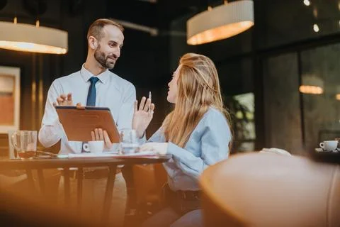 Two colleagues discussing work at a modern cafe setting during the day Stock Photos
