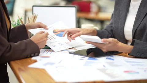 Two colleagues engaged in business analytics, using calculator over financial Stock Footage 280816228