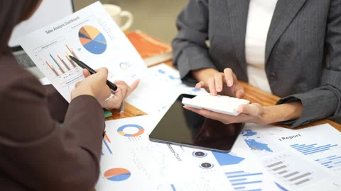 Two colleagues engaged in business analytics, using calculator over financial Stock Footage 280816230