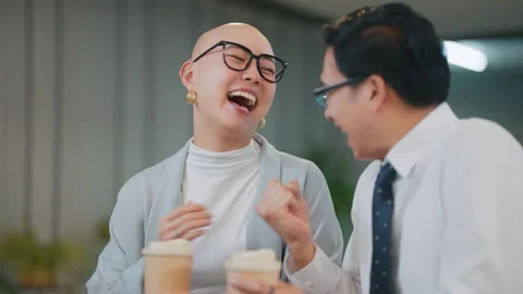 Two colleagues laugh together over coffee in an office Stock Footage 346682019