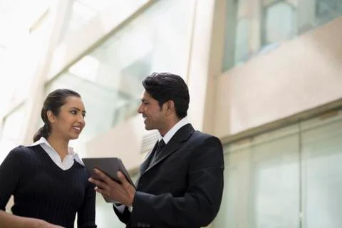 Two colleagues looking at a digital tablet outside office building Stock Photos