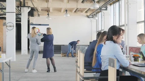 Two colleagues make a presentation on a flipchart. Next to the big table are the Stock Footage 109368612