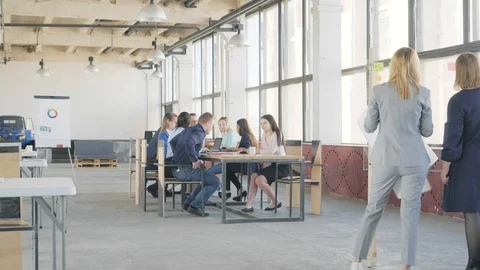 Two colleagues make a presentation on a glass board. Employees sit at a large Stock Footage 109371293
