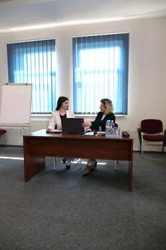 Two colleagues review documents at an office desk beside a laptop while discu Stock-Fotos