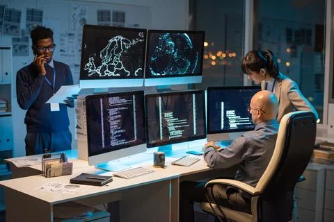 Two colleagues sitting in front of computer monitors with decoded data Stock Photos