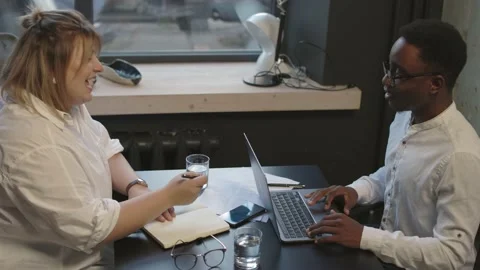 Two colleagues sitting at the table and discussing startup in modern office Stock Footage 166060655