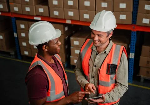 Two colleagues smiling while discussing business plans holding digital tablet Stock Photos