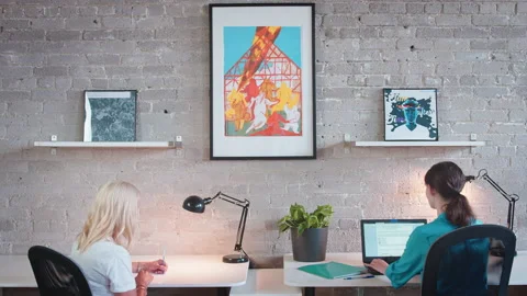 Two colleagues social distance at work while using their electronics, computers, Stock Footage 137042738