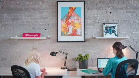 Two colleagues social distance at work while using their electronics, computers, Stock Footage 137042860