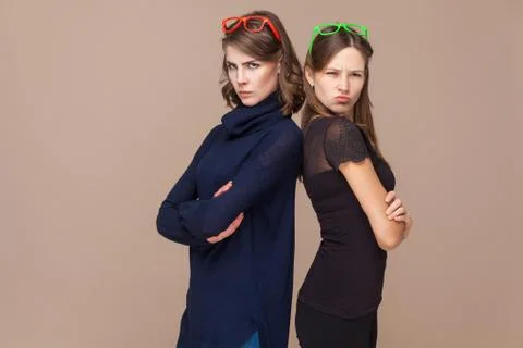 Two colleagues standing back to back and looking at camera seriously. Foto stock