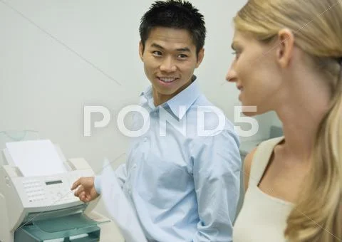Two Colleagues Standing Near Fax Machine