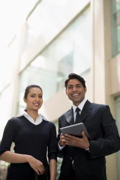 Two colleagues standing outside office smiling at camera Stock Photos
