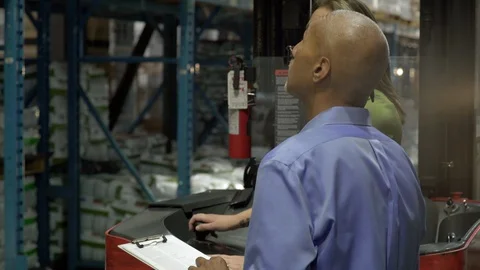 Two colleagues talking and operating warehouse machinery. 動画素材 88029209