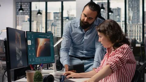 Two colleagues waiting for AI text to video generating on computer Stock-Fotos